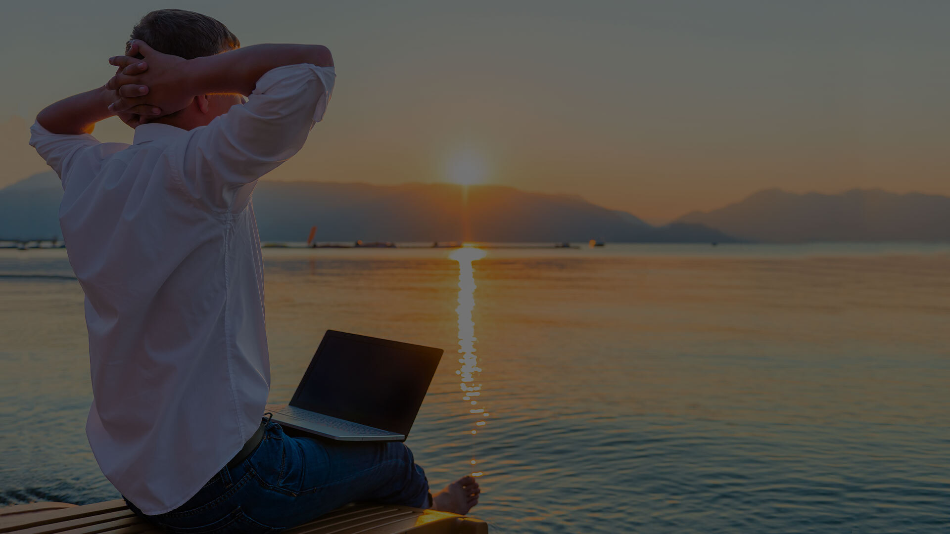 Moving from Work-Life Balance to Work-Life Freedom and How Businesses Can Help work-life freedom | person sits on beach with their arms behind their head, relaxing with their laptop in their lap