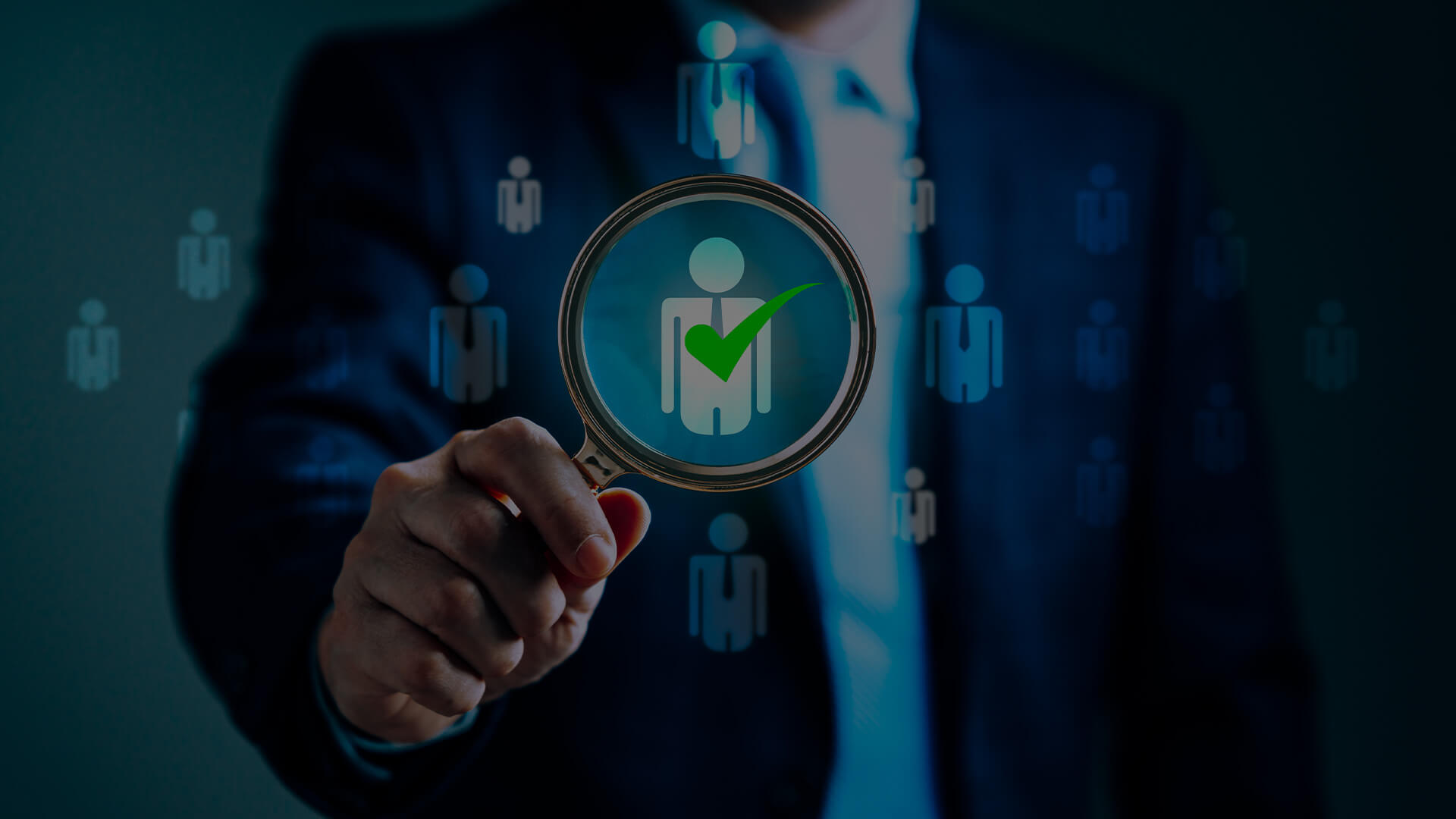 Close-up of a person holding a magnifying glass, focusing on a human icon with a green checkmark, symbolizing the effectiveness of a recruitment strategy. The background features multiple icons of people, highlighting the process of selecting the right candidate.