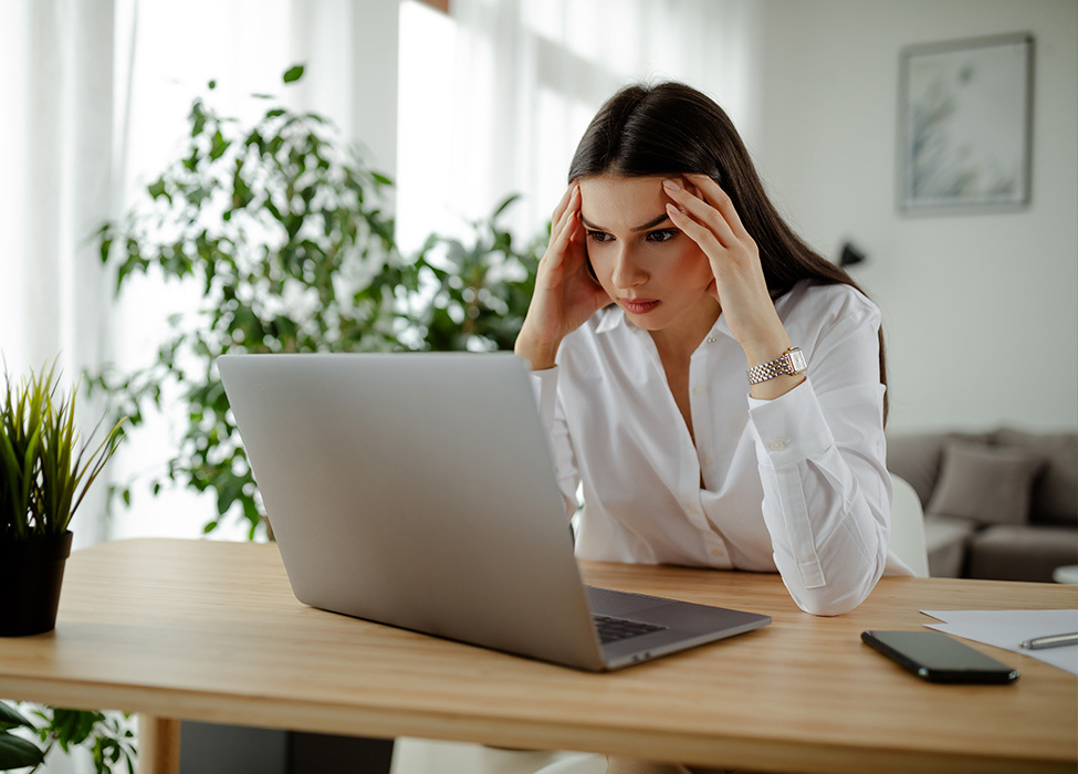 Business Technology: Person appears frustrated with their head resting against their fingertips as they stare at their laptop