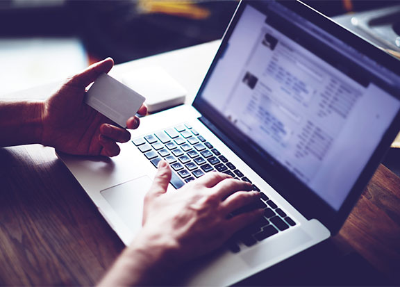 Transaction Management | Close up of person holding a credit card and paying a bill on their laptop