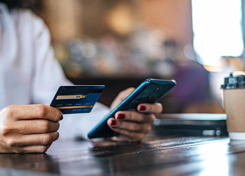 Person holding a credit card in one hand while on their phone with the other hand