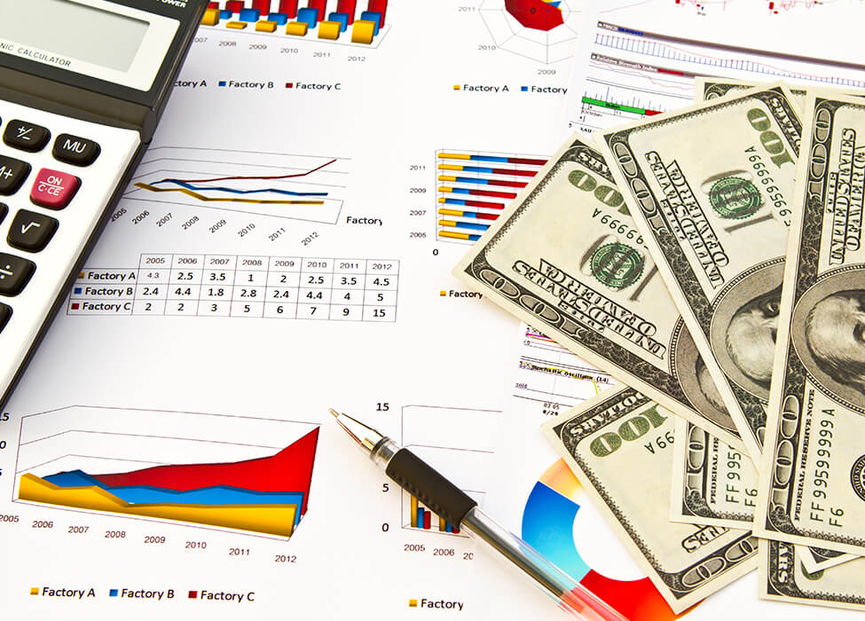 A close up of scattered papers, a calculator, a pen, and four one-hundred dollar bills