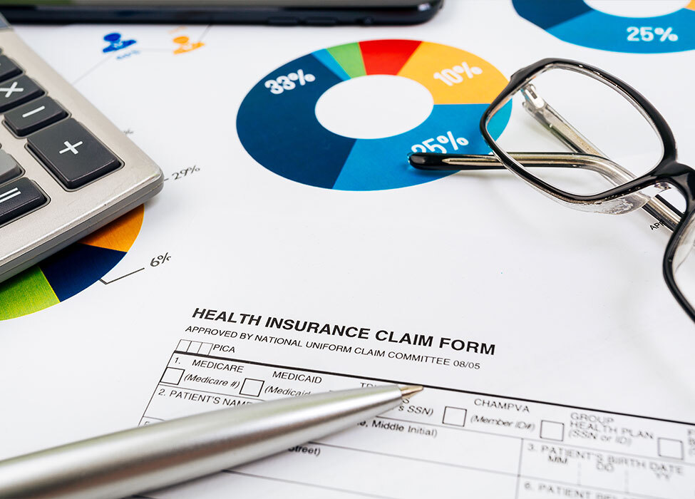 Denial Management in Healthcare | Close up image of scattered items including papers with graphs on them and a pair of glasses